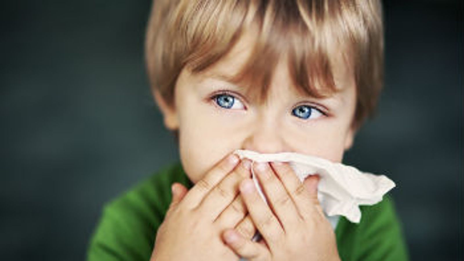 Child blowing nose into a tissue