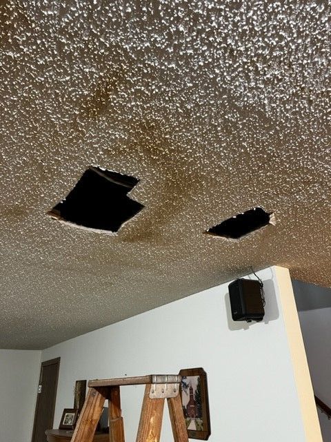 Access holes cut into ceiling to repair plumbing leak